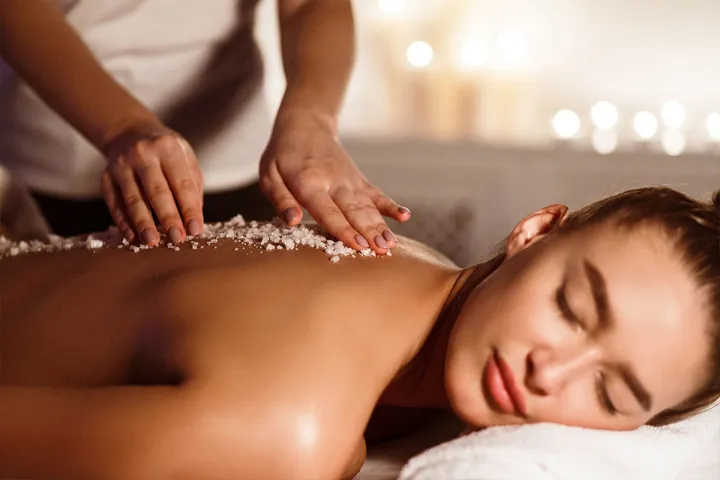 Frau entspannt bei einer Massage mit Meersalz im Well-Being-Spa des Grand Hotel Binz auf Rügen.