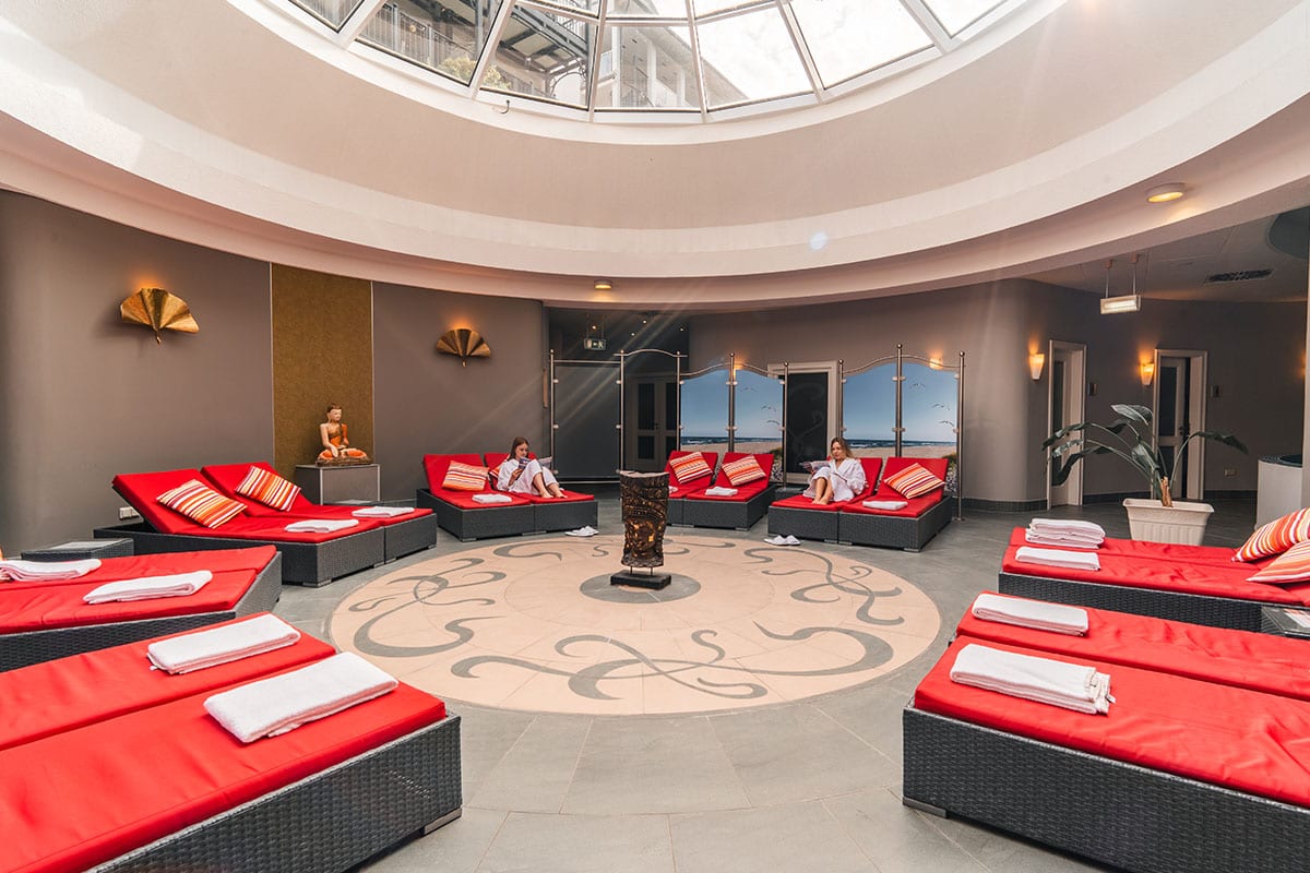 Circular loungers with pillows under bright glass roof in spa area